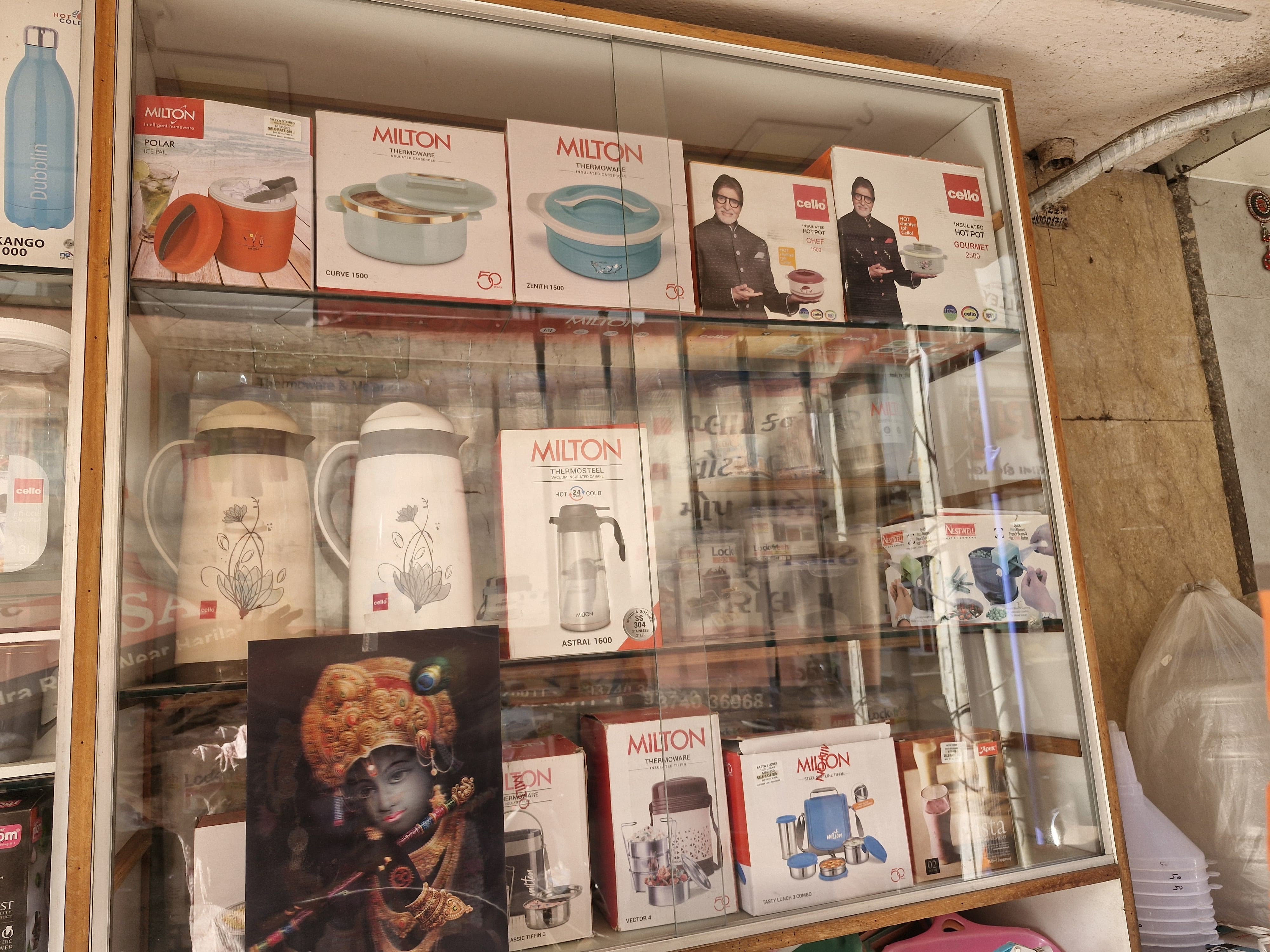 Glass display case featuring Milton containers and decorative religious artwork